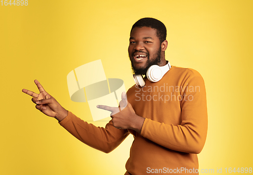 Image of Young african-american man\'s portrait isolated on yellow studio background, facial expression. Beautiful male half-lenght portrait with copyspace.