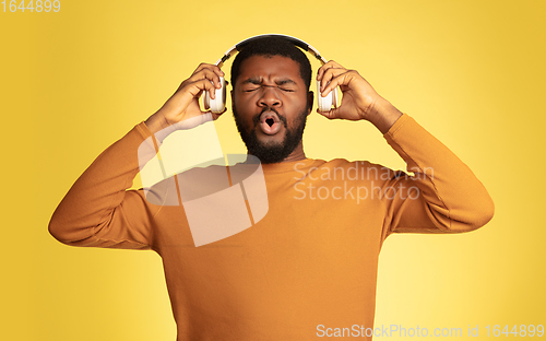 Image of Young african-american man\'s portrait isolated on yellow studio background, facial expression. Beautiful male half-lenght portrait with copyspace.