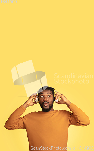 Image of Young african-american man\'s portrait isolated on yellow studio background, facial expression. Beautiful male half-lenght portrait with copyspace.