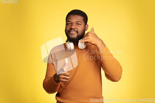 Image of Young african-american man\'s portrait isolated on yellow studio background, facial expression. Beautiful male half-lenght portrait with copyspace.