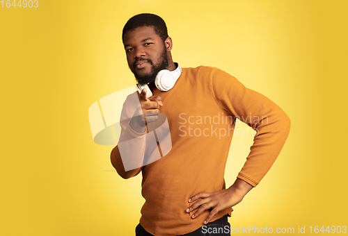 Image of Young african-american man\'s portrait isolated on yellow studio background, facial expression. Beautiful male half-lenght portrait with copyspace.