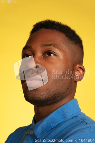 Image of Young african-american man\'s portrait isolated on yellow studio background, facial expression. Beautiful male half-lenght portrait with copyspace.