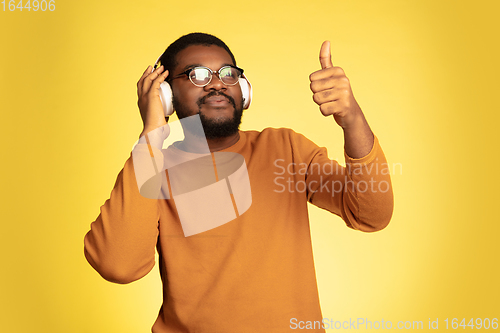 Image of Young african-american man\'s portrait isolated on yellow studio background, facial expression. Beautiful male half-lenght portrait with copyspace.