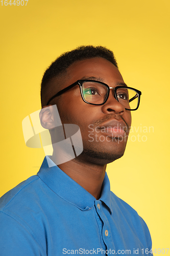 Image of Young african-american man\'s portrait isolated on yellow studio background, facial expression. Beautiful male half-lenght portrait with copyspace.