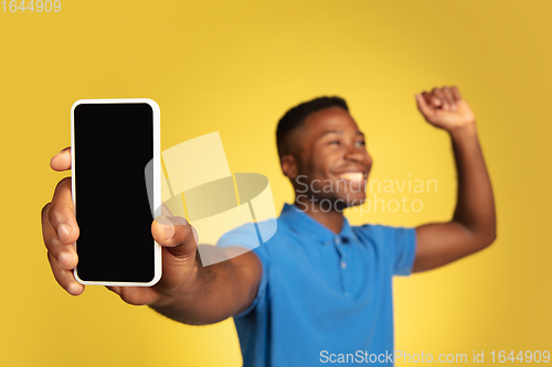 Image of Young african-american man\'s portrait isolated on yellow studio background, facial expression. Beautiful male half-lenght portrait with copyspace.