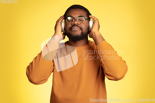 Image of Young african-american man\'s portrait isolated on yellow studio background, facial expression. Beautiful male half-lenght portrait with copyspace.