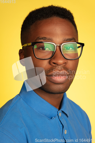 Image of Young african-american man\'s portrait isolated on yellow studio background, facial expression. Beautiful male half-lenght portrait with copyspace.