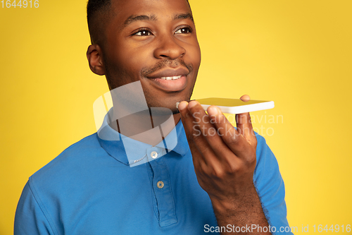 Image of Young african-american man\'s portrait isolated on yellow studio background, facial expression. Beautiful male half-lenght portrait with copyspace.