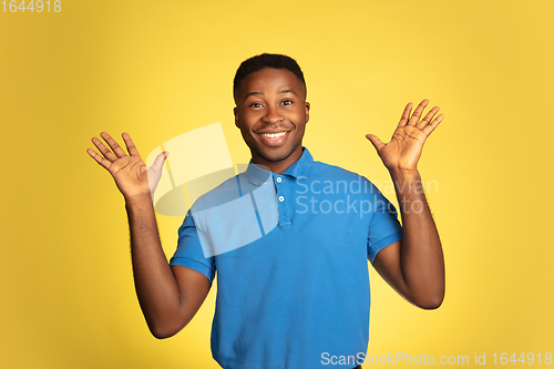 Image of Young african-american man\'s portrait isolated on yellow studio background, facial expression. Beautiful male half-lenght portrait with copyspace.