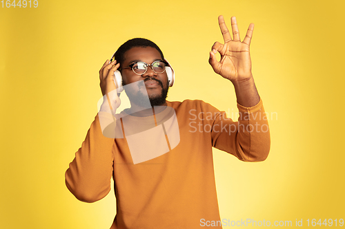 Image of Young african-american man\'s portrait isolated on yellow studio background, facial expression. Beautiful male half-lenght portrait with copyspace.