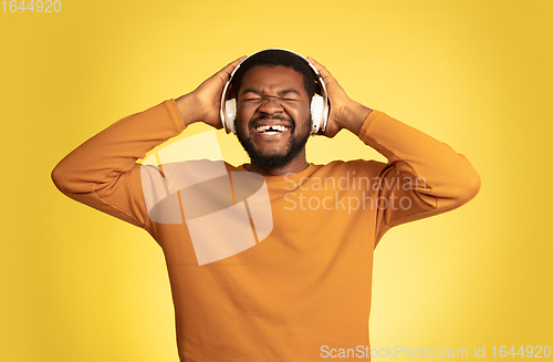 Image of Young african-american man\'s portrait isolated on yellow studio background, facial expression. Beautiful male half-lenght portrait with copyspace.