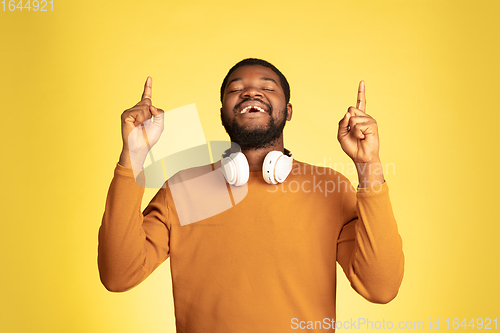 Image of Young african-american man\'s portrait isolated on yellow studio background, facial expression. Beautiful male half-lenght portrait with copyspace.