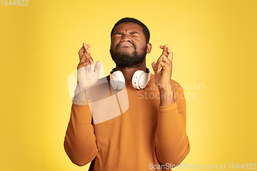 Image of Young african-american man\'s portrait isolated on yellow studio background, facial expression. Beautiful male half-lenght portrait with copyspace.