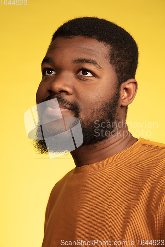 Image of Young african-american man\'s portrait isolated on yellow studio background, facial expression. Beautiful male half-lenght portrait with copyspace.