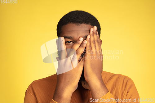 Image of Young african-american man\'s portrait isolated on yellow studio background, facial expression. Beautiful male half-lenght portrait with copyspace.