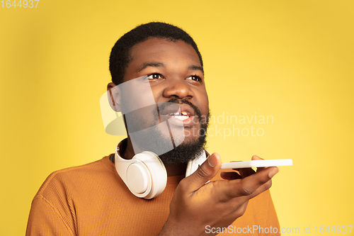 Image of Young african-american man\'s portrait isolated on yellow studio background, facial expression. Beautiful male half-lenght portrait with copyspace.