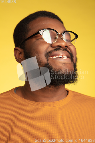 Image of Young african-american man\'s portrait isolated on yellow studio background, facial expression. Beautiful male half-lenght portrait with copyspace.