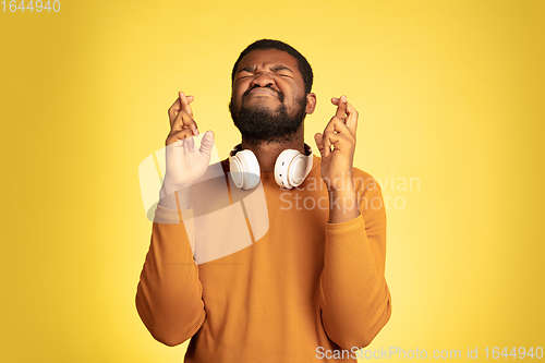 Image of Young african-american man\'s portrait isolated on yellow studio background, facial expression. Beautiful male half-lenght portrait with copyspace.