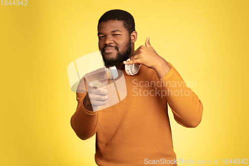 Image of Young african-american man\'s portrait isolated on yellow studio background, facial expression. Beautiful male half-lenght portrait with copyspace.