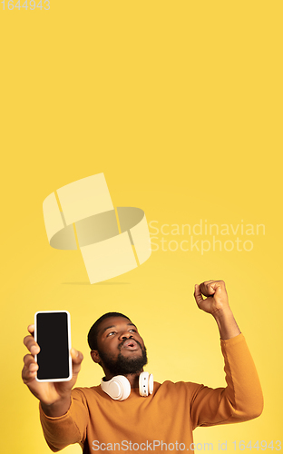 Image of Young african-american man\'s portrait isolated on yellow studio background, facial expression. Beautiful male half-lenght portrait with copyspace.