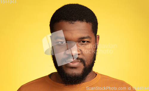 Image of Young african-american man\'s portrait isolated on yellow studio background, facial expression. Beautiful male half-lenght portrait with copyspace.