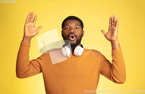 Image of Young african-american man\'s portrait isolated on yellow studio background, facial expression. Beautiful male half-lenght portrait with copyspace.