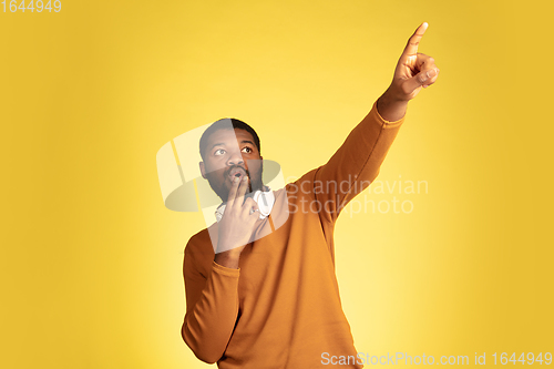 Image of Young african-american man\'s portrait isolated on yellow studio background, facial expression. Beautiful male half-lenght portrait with copyspace.