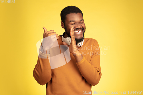 Image of Young african-american man\'s portrait isolated on yellow studio background, facial expression. Beautiful male half-lenght portrait with copyspace.