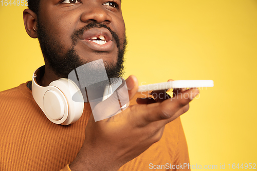 Image of Young african-american man\'s portrait isolated on yellow studio background, facial expression. Beautiful male half-lenght portrait with copyspace.