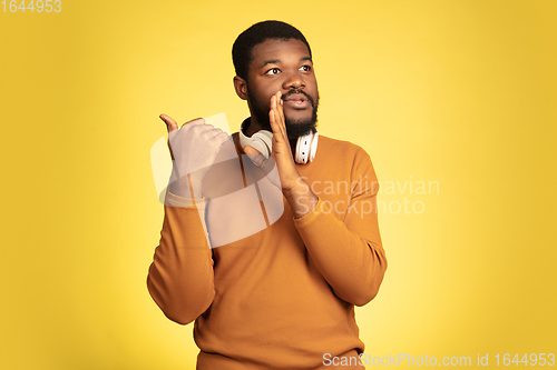 Image of Young african-american man\'s portrait isolated on yellow studio background, facial expression. Beautiful male half-lenght portrait with copyspace.