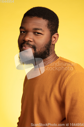 Image of Young african-american man\'s portrait isolated on yellow studio background, facial expression. Beautiful male half-lenght portrait with copyspace.