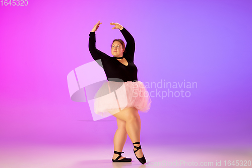 Image of Beautiful caucasian plus size model practicing ballet dance on gradient purple-pink studio background in neon light