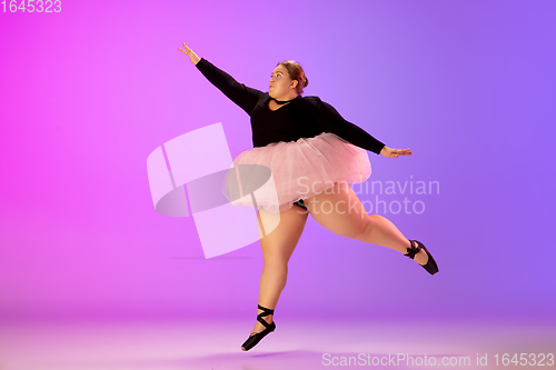 Image of Beautiful caucasian plus size model practicing ballet dance on gradient purple-pink studio background in neon light