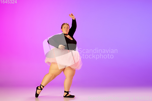 Image of Beautiful caucasian plus size model practicing ballet dance on gradient purple-pink studio background in neon light