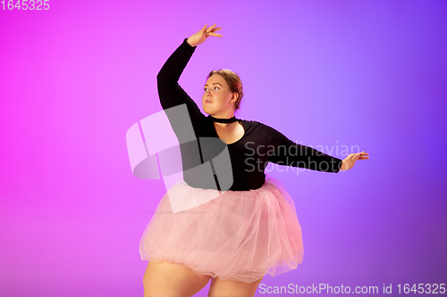 Image of Beautiful caucasian plus size model practicing ballet dance on gradient purple-pink studio background in neon light