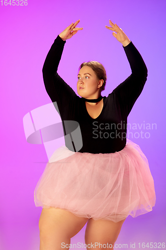 Image of Beautiful caucasian plus size model practicing ballet dance on gradient purple-pink studio background in neon light