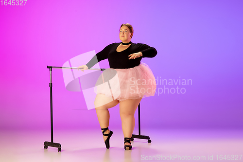 Image of Beautiful caucasian plus size model practicing ballet dance on gradient purple-pink studio background in neon light