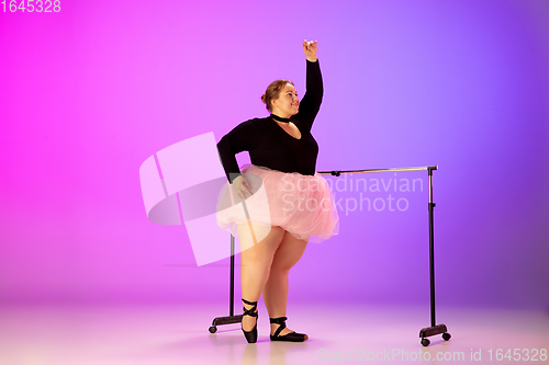 Image of Beautiful caucasian plus size model practicing ballet dance on gradient purple-pink studio background in neon light