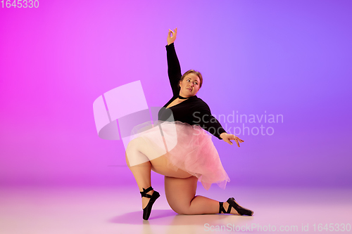 Image of Beautiful caucasian plus size model practicing ballet dance on gradient purple-pink studio background in neon light