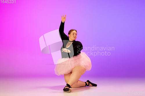 Image of Beautiful caucasian plus size model practicing ballet dance on gradient purple-pink studio background in neon light