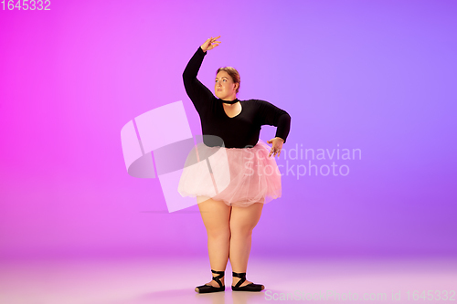 Image of Beautiful caucasian plus size model practicing ballet dance on gradient purple-pink studio background in neon light