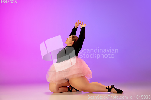 Image of Beautiful caucasian plus size model practicing ballet dance on gradient purple-pink studio background in neon light