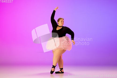 Image of Beautiful caucasian plus size model practicing ballet dance on gradient purple-pink studio background in neon light