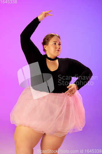 Image of Beautiful caucasian plus size model practicing ballet dance on gradient purple-pink studio background in neon light