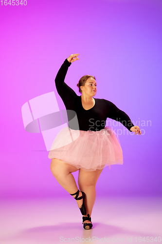 Image of Beautiful caucasian plus size model practicing ballet dance on gradient purple-pink studio background in neon light