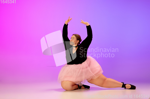 Image of Beautiful caucasian plus size model practicing ballet dance on gradient purple-pink studio background in neon light