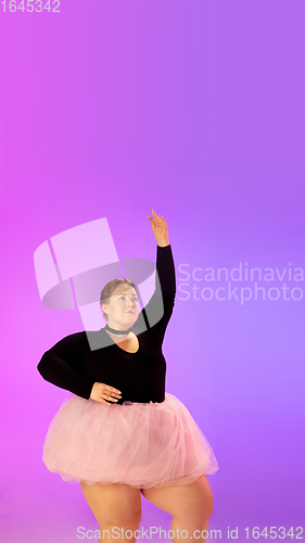 Image of Beautiful caucasian plus size model practicing ballet dance on gradient purple-pink studio background in neon light