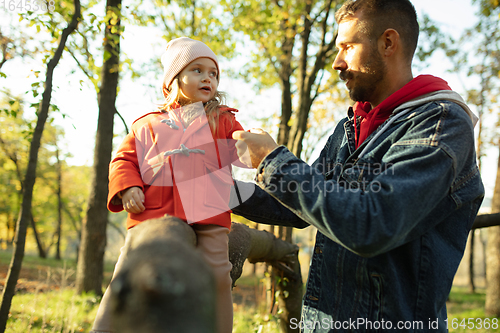 Image of Happy father and little cute daughter walking down the forest path in autumn sunny day