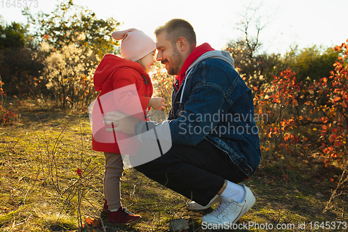 Image of Happy father and little cute daughter walking down the forest path in autumn sunny day