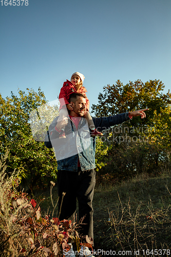 Image of Happy father and little cute daughter walking down the forest path in autumn sunny day